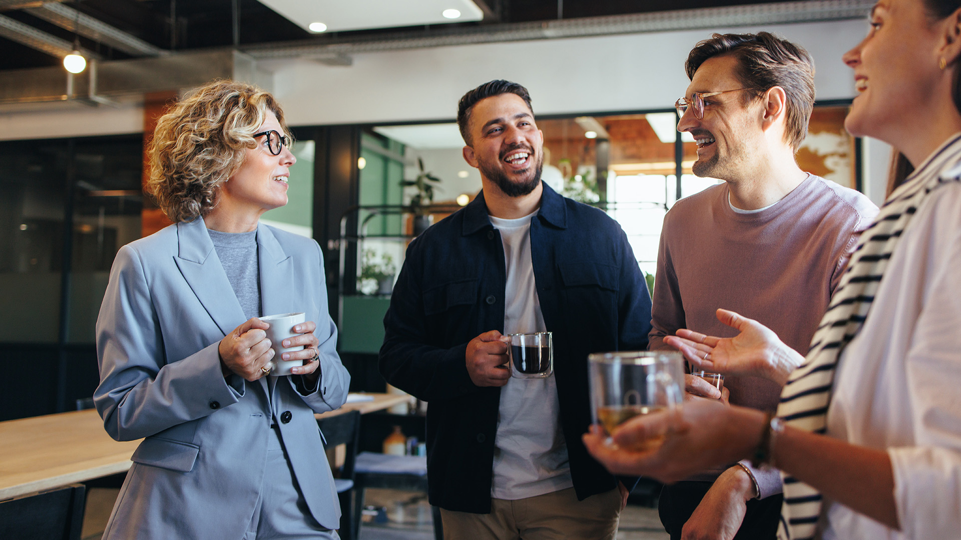 A group of happy colleagues standing together drinking coffee (The Alexander Partnership)